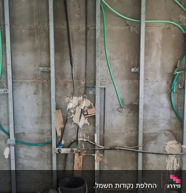 קירות חשופים עם צינורות חשמל ירוקים ושחורים